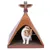 Chat blanc et roux à l’intérieur d’une maisonnette tipi en carton décorée de motifs colorés, avec un totem au sommet. Sol en carton visible.
