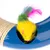 Toy mouse with yellow fur, green and pink tail in a blue plastic ring with sisal rope elements.