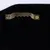 Primer plano de un colgador de metal dorado con borde dentado, fijado a una superficie negra.