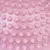 Primo piano di una superficie rosa con rilievi a forma di nodi, possibile struttura del materiale di un prodotto.
