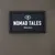 Nomad Tales München. Metka marki na brązowej tkaninie.
