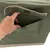 Bolso verde con cierre de velcro, una mano abre el compartimento exterior. Vista detallada de la funcionalidad del espacio de almacenamiento.