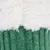 Close-up of green ribbed fabric with white fluffy material on top. Texture and materials details visible.