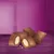 Nahaufnahme von braunen Snacks mit knuspriger Hülle und heller Füllung, auf violettem Hintergrund präsentiert.