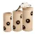 Three beige cylindrical scratching towers with multiple entry holes and hanging toys, shown in different heights. A cat is standing on the tallest tower.