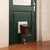 Cat flap in green door, with a cat passing through. Shows the function of the flap for pets.
