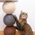 Cat scratching a scratching post with sisal balls in various colours: beige, grey and brown.