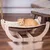 Amaca in legno con superficie color crema, sopra un gatto arancione sdraiato.