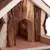 Entrée d’une maisonnette pour petits animaux en bois brut, avec façade et toit visibles, matériaux naturels apparents.