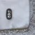 Étiquette avec le nom de la marque Tiaki sur tissu gris à bordure en fausse fourrure bouclée.