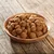 Brown dry food pieces in a wooden bowl on a wooden table. No further visible information.