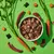 Bowl of cubed pet food surrounded by raw carrots, carrot slices, meat strips, rice grains and seaweed pieces, showing visible ingredients used in the product.