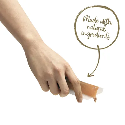 Рука держит упаковку с пастообразным кормом, выдавливаемым наружу. Видна надпись на английском: Made with natural ingredients.