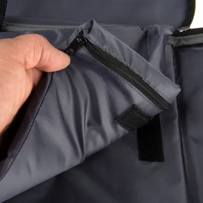 Gros plan sur une main ouvrant une poche zippée en tissu gris avec fermeture velcro visible, détail d’un accessoire ou sac pour animaux.