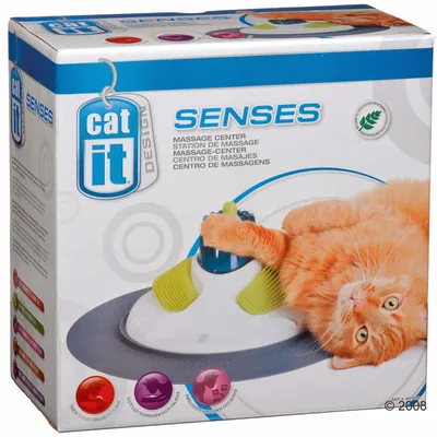 Catit Design Senses Masážní centrum. Obal zobrazuje oranžovou kočku s masážním přístrojem. Obsahuje text: Massage-Center, Station de Massage, Centro de Masajes. Certifikát bezpečných materiálů.