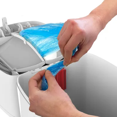 Hände ziehen einen blauen Müllbeutel aus einem weissen Behälter mit geöffnetem Deckel. Demonstration der Beutelentnahme.