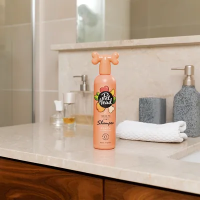 Pet Head Quick Fix 2-in-1 shampoo persikka ja arganöljy, 300 ml pullo kylpyhuoneen hyllyllä.