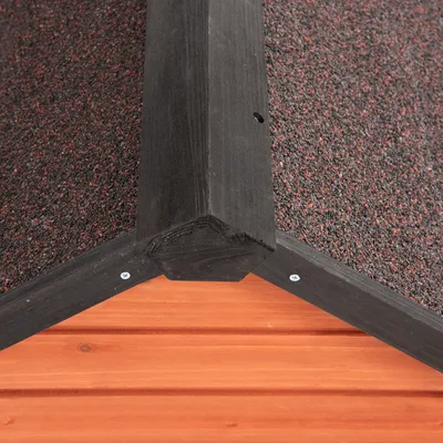 Detailweergave van een houten dakgevel met zwart frame en rood-zwarte dakbedekking.