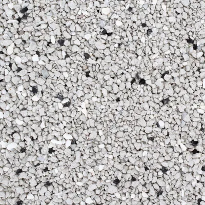 Detailní pohled na šedý hrubozrnný materiál s černými a bílými částicemi, zobrazení struktury podestýlky nebo steliva.