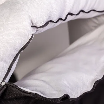 Gros plan sur un tissu blanc rembourré à motif géométrique avec bordure noire.