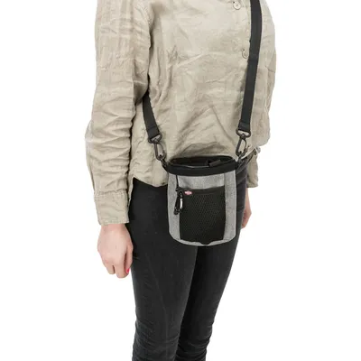 Grey treat bag with adjustable shoulder strap, mesh pocket and zip, worn by a person. Suitable for on the go.