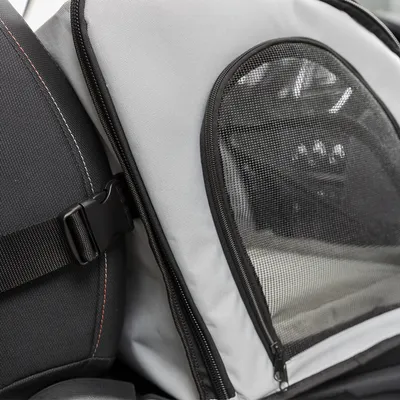 Transport bag with mesh window and seat belt attachment, suitable for car seats. Close-up of attachment and material.