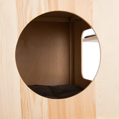 Holzverkleidete Höhle mit rundem Eingang und gepolstertem Innenboden, geeignet als Rückzugsort.