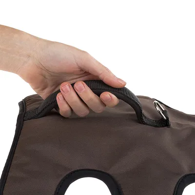 Ręka trzyma czarny uchwyt z wytrzymałego materiału, przymocowany do brązowej tkaniny z metalowym pierścieniem.