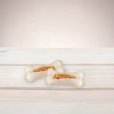 Two chew bones with dried meat filling on a light wooden table.