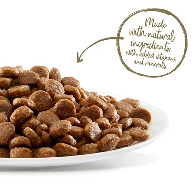 Bord met bruine brokjes. Tekst in beeld: Made with natural ingredients with added vitamins and minerals (Engels).