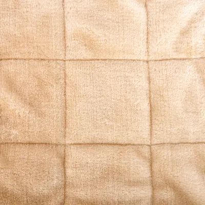 Detalle de superficie acolchada de tela beige con costuras visibles formando cuadrados. Material textil suave, adecuado para productos como camas o mantas para mascotas.