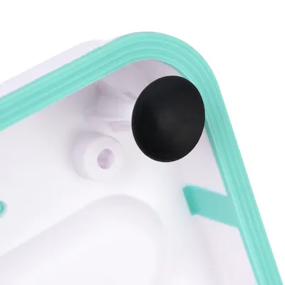 Close-up of a white plastic surface with a turquoise edge and black rubber foot. Fastening elements are visible.