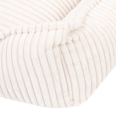 Nahaufnahme eines cremefarbenen, gerippten Stoffmaterials mit weicher Polsterung. Detailansicht eines Produkts für Heimtierbedarf.