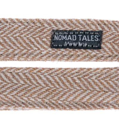Nomad Tales lettering on brown and white fabric with herringbone pattern.