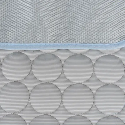 Zbliżenie na szarą, pikowaną powierzchnię z okrągłym wzorem i jasnoniebieską siateczką na wierzchu.