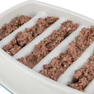 Close-up of wet food in a white feeding bowl with vertical grooves portioning the food.