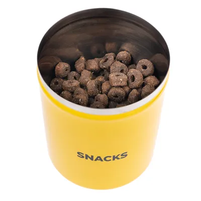 Yellow tin with the inscription 'SNACKS', filled with brown, ring-shaped treats.