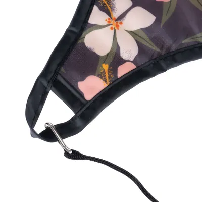 Detailansicht eines Stoffmaterials mit Blumenmuster, schwarzem Rand und Metallclip mit Schnur.