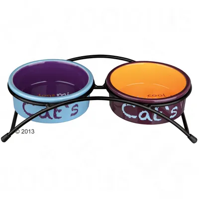 Dubbele kattenvoerbak van keramiek in houder, linker bak paars met tekst 'Cat's', rechter bak oranje met tekst 'Cat's', metalen standaard inbegrepen.