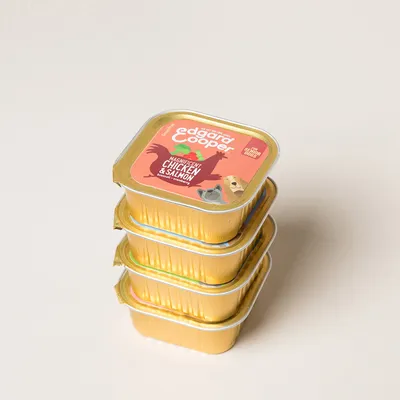 Vier goudkleurige bakjes Edgard & Cooper natvoer, zichtbare tekst: 'Magnificent Chicken & Salmon', afbeelding van kip en zalm op de verpakking.