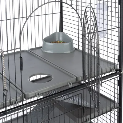 Colivie pentru păsări cu tăvițe din plastic gri, stație de hrănire cu semințe și sticlă de apă. Grilaj metalic cu ușă vizibilă.