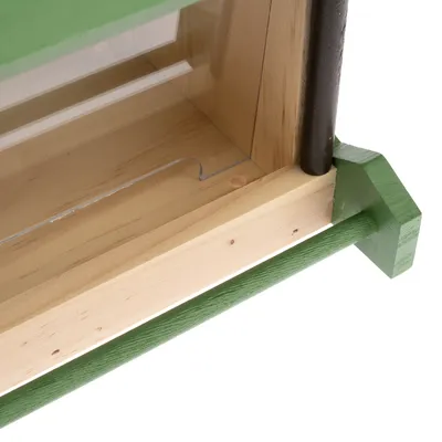 Vista dettagliata di una cornice in legno con elementi verniciati di verde e inserto in plexiglas.