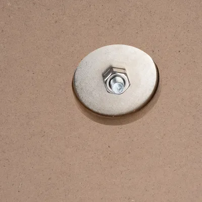 Close-up of a metal nut and screw on a wooden surface, showing a fastening element for a product.