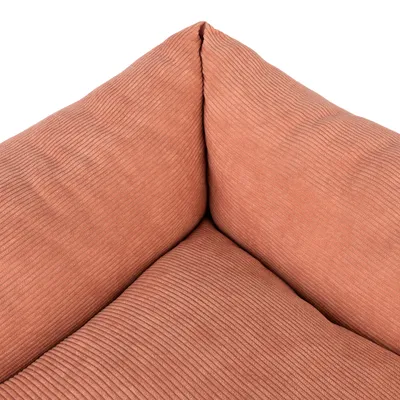 Povečava oranžnega, rebrastega tekstila z oblazinjenimi vogali. Podroben pogled na material za posteljo za hišne ljubljenčke ali kos pohištva.