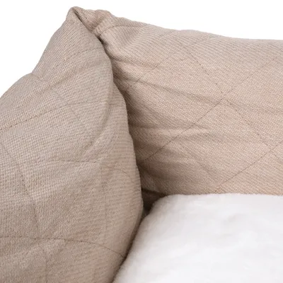 Nahaufnahme eines beigen, gesteppten Stoffbezugs und einer weissen, weichen Polsterung. Materialdetails des Produkts sichtbar.