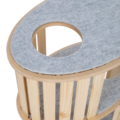Structure ovale en bois avec plateau supérieur et intérieur recouverts de feutre gris, ouverture circulaire visible sur le dessus. Matériaux visibles : bois et feutre.
