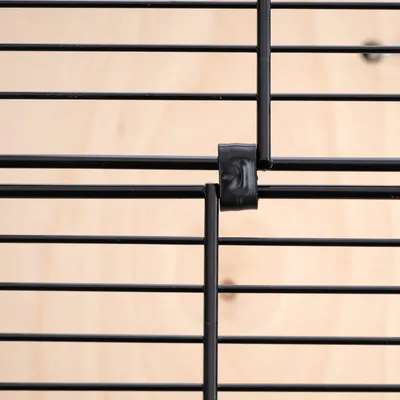 Detaljebillede af sort metalgitter med plastklips til sammenkobling af gitterelementer.