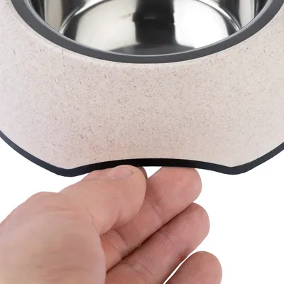Hand zeigt rutschfeste Unterseite eines Futternapfs mit Edelstahl-Innenschale und beige Aussenmaterial.