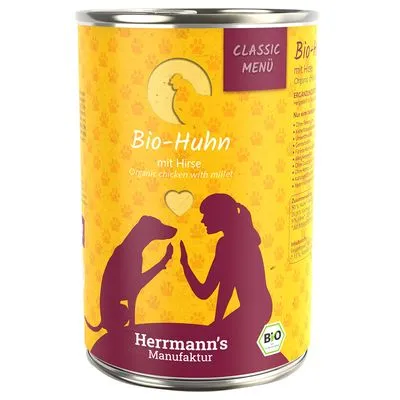 Herrmann's Manufaktur Bio-Huhn mit Hirse, Classic Menü. Blik met afbeelding van hond en persoon, label vermeldt biologisch kip met gierst. Bio-keurmerk zichtbaar.