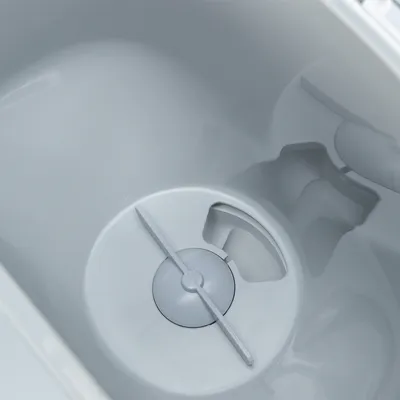 Detailní záběr na bílou nádobu s integrovaným míchacím mechanismem a výřezy na tekutiny nebo krmivo.